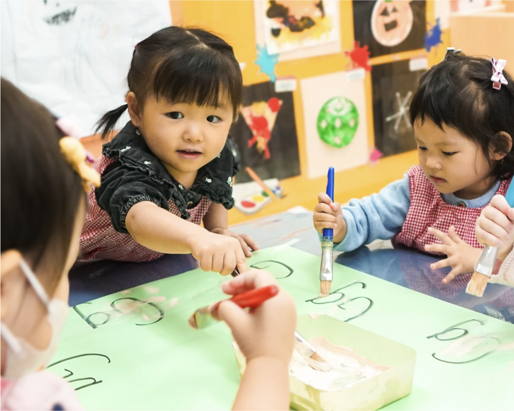 Children are learning the letter G with g-litter and g-lue in a small group activity