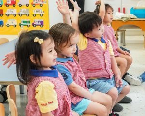 Children are raising their hands to be chosen for the Reggio activities